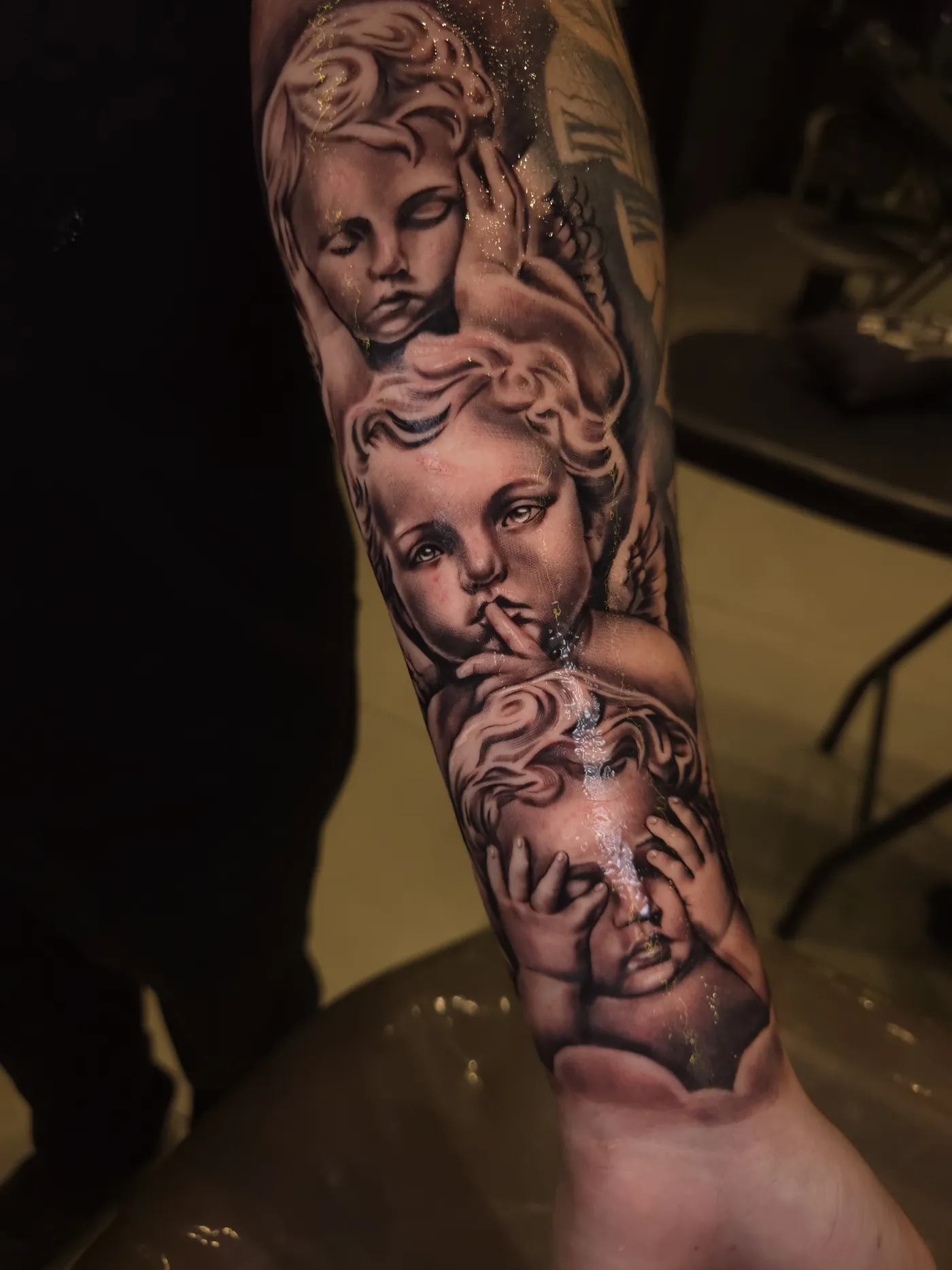 Tatuagem realista de rostos em preto e cinza no braço